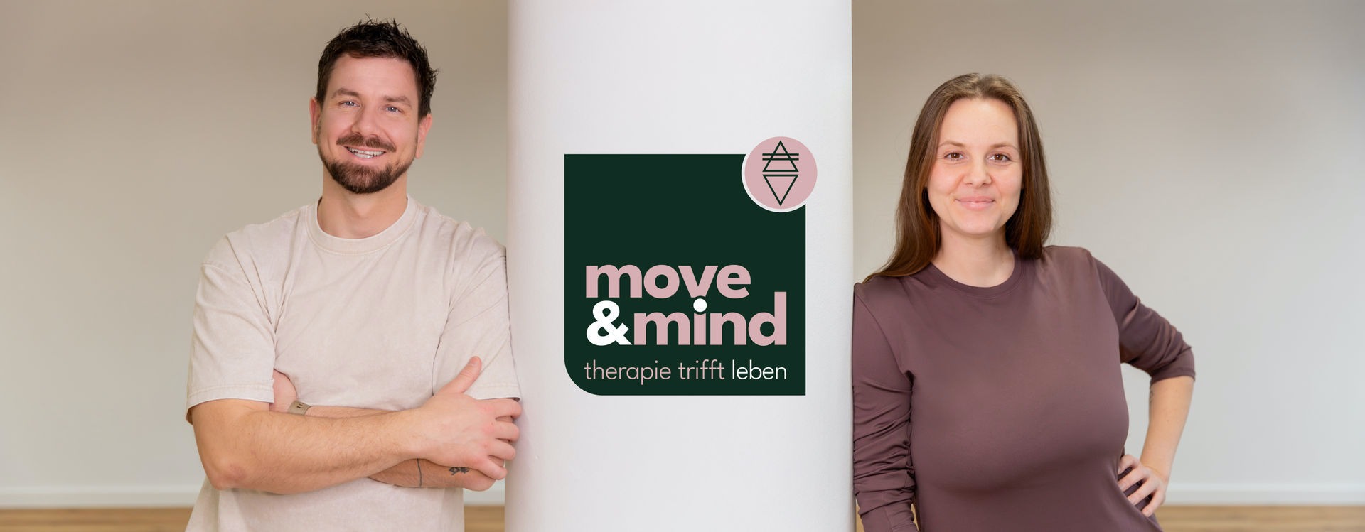Physio-Yoga-Training-Praxis-Move&Mind-HH-Harburg Lächelnde Mitja und Anne von Move & Mind an einer Säule lehnend