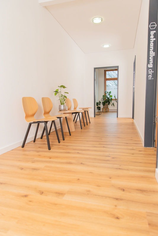 Wartebereich-Flur Heller Flur mit vier Stühlen und einer Pflanze