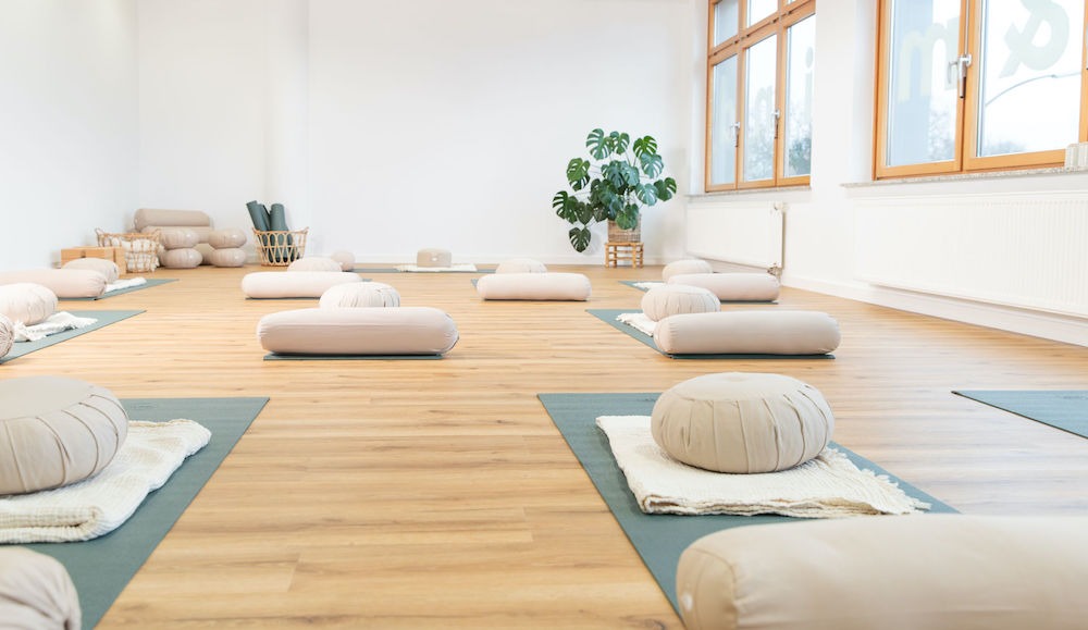 Yogastudio-HH-Harburg-Move-and-Mind Helles Yogastudio mit sandfarbenen Kissen, hellblauen Matten und Pflanze